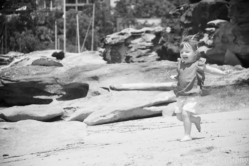 Little girl running with glee along the beach - family portrait photography sydney
